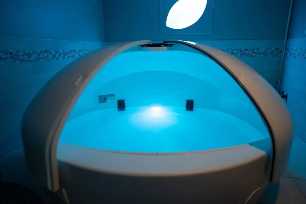 Modern float pod with blue lighting at True REST Float Spa, used for holistic wellness and relaxation